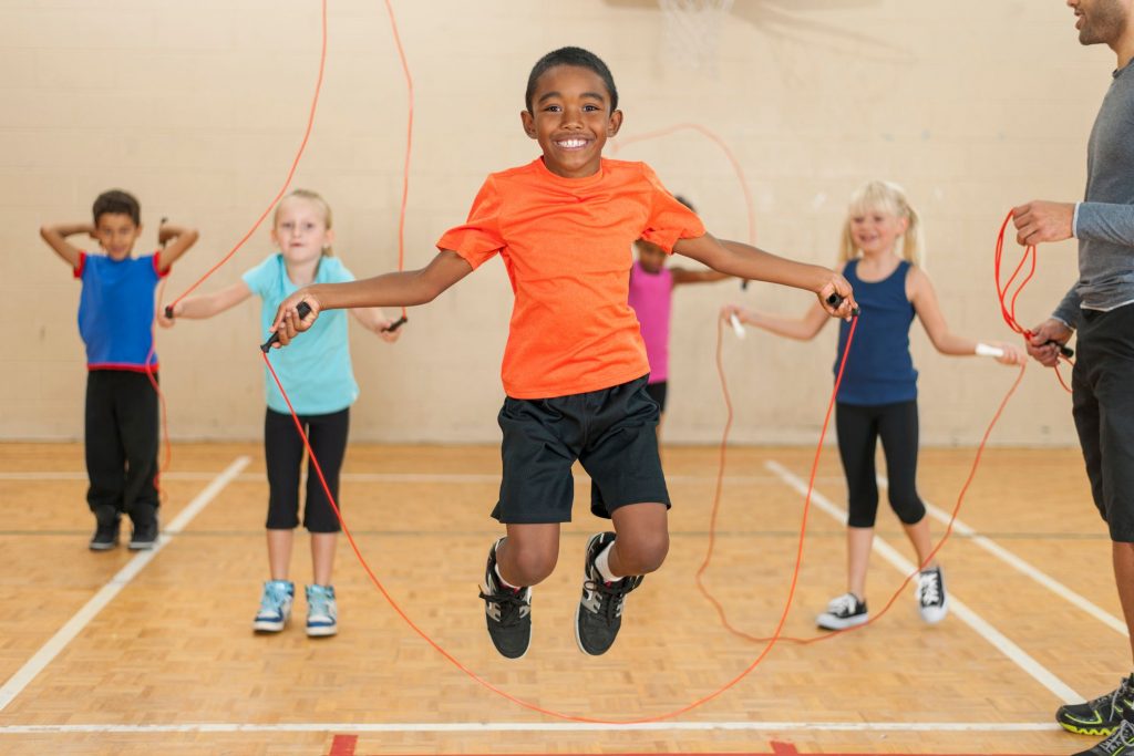 Students in school gym with jump ropes.